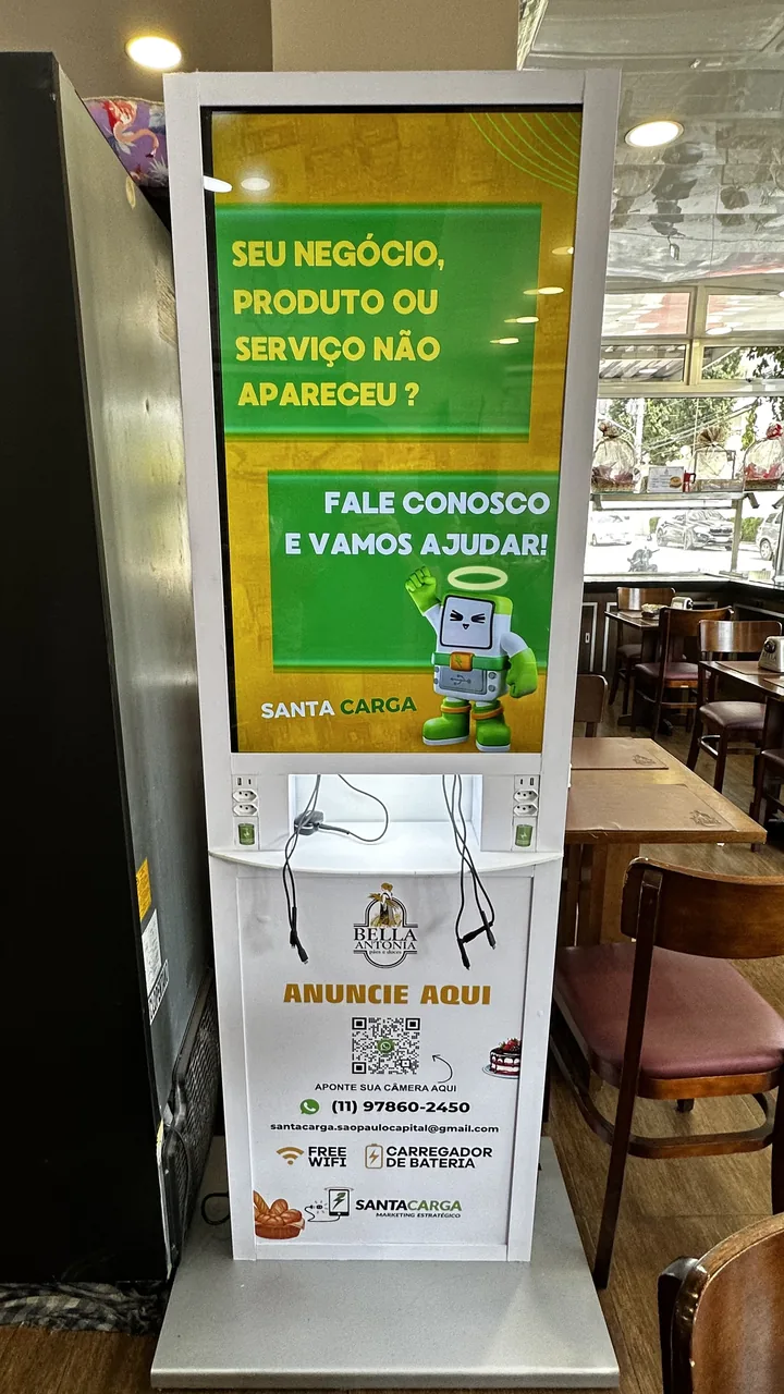 Totem de mídia Santa Carga na Padaria Bella Antonia, com tela de 40 polegadas e recarga de celular